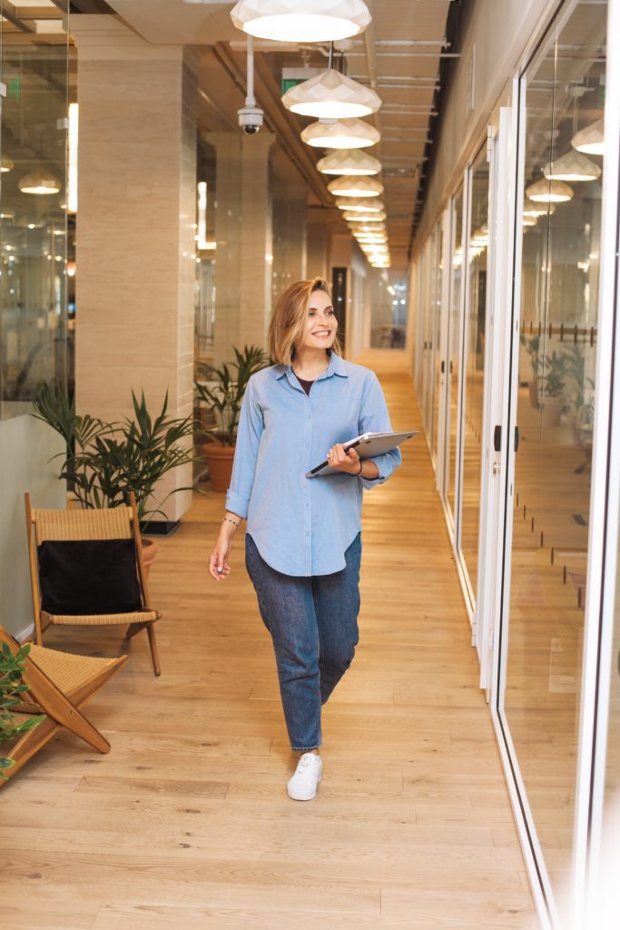 Girl in a blue shirt walking in a hallway smiling